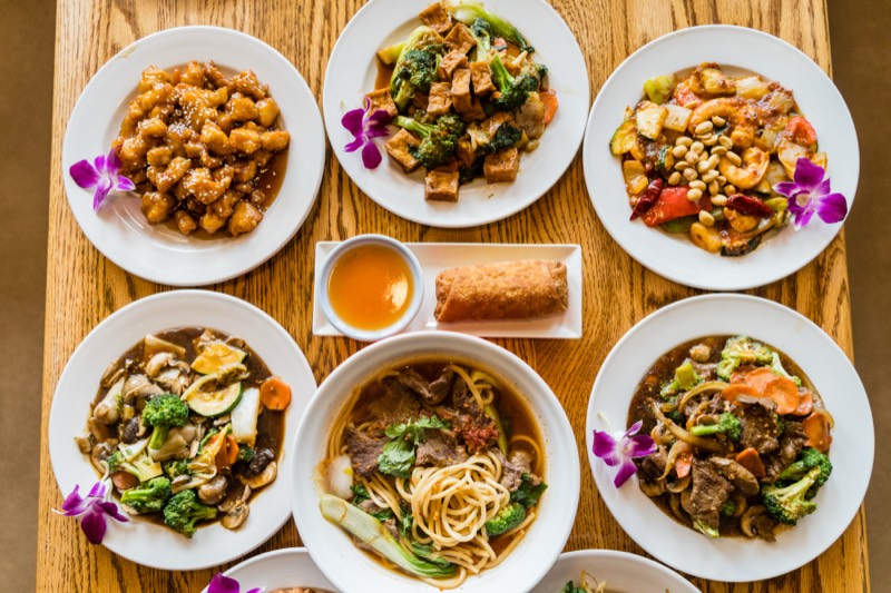 Autumn Court family-style catering spread with egg roll and eight dishes